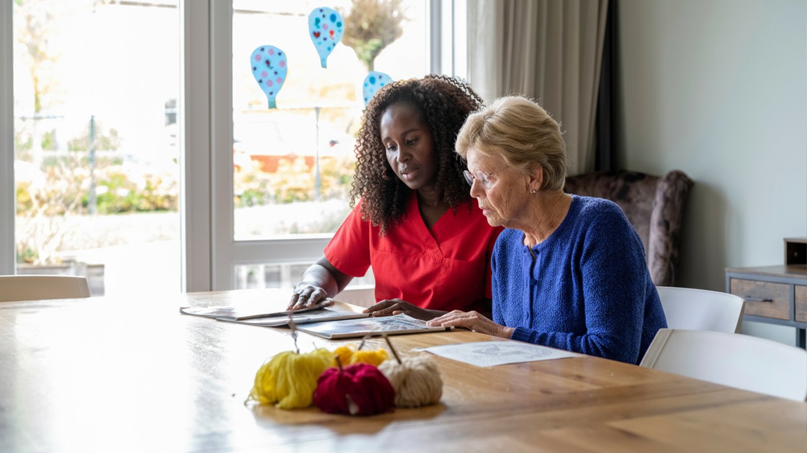Home Caregiver looking through magazines with senior